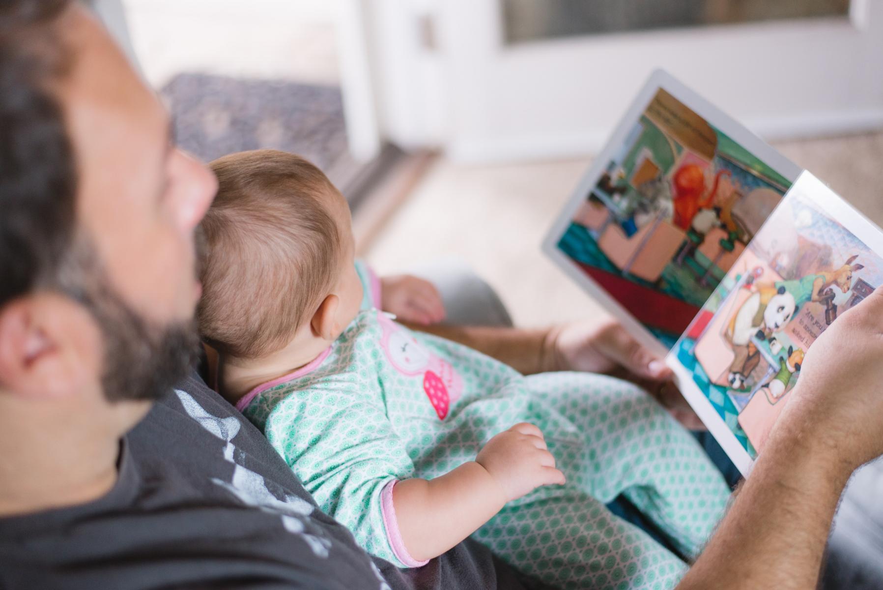 Parent reading a picture book to an infant