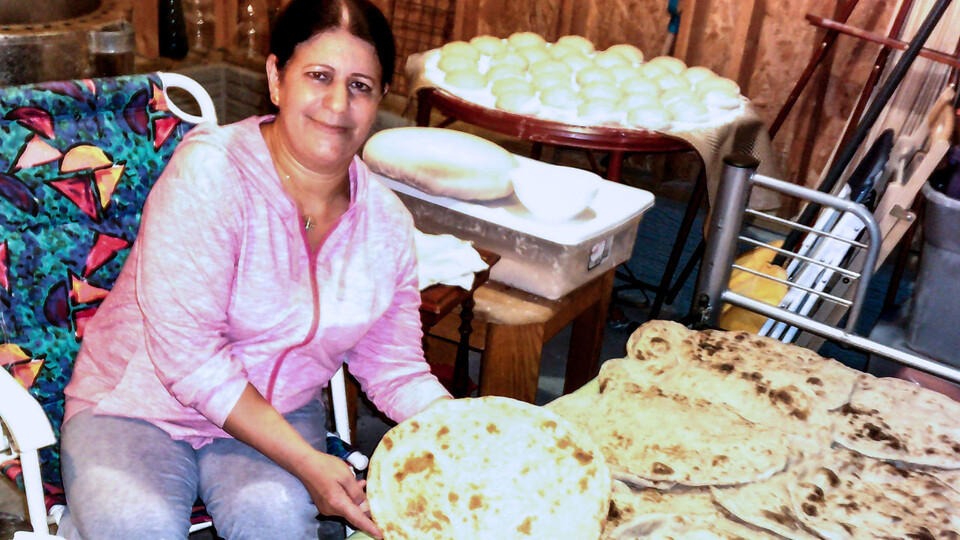 A Yazidi woman shows off a large batch of naan, a round, flat, leavened bread. 