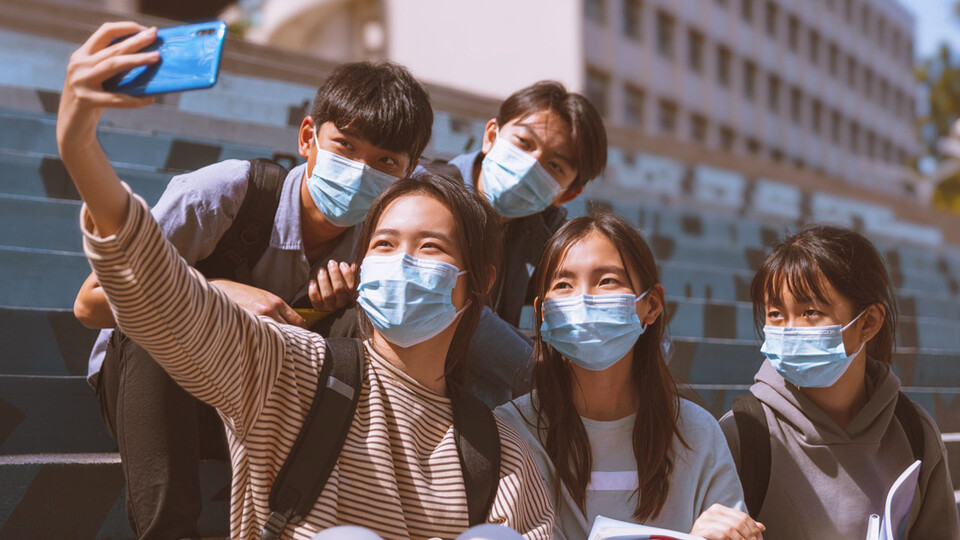 Asian students wearing masks taking a selfie with a phone