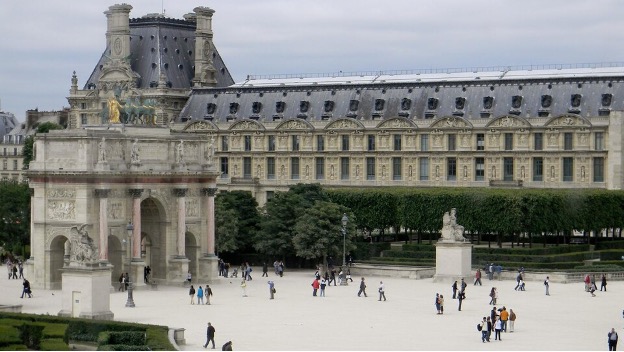 People walking at the Arc de Triomphe du Carrousel outside the Louvre in Paris.
