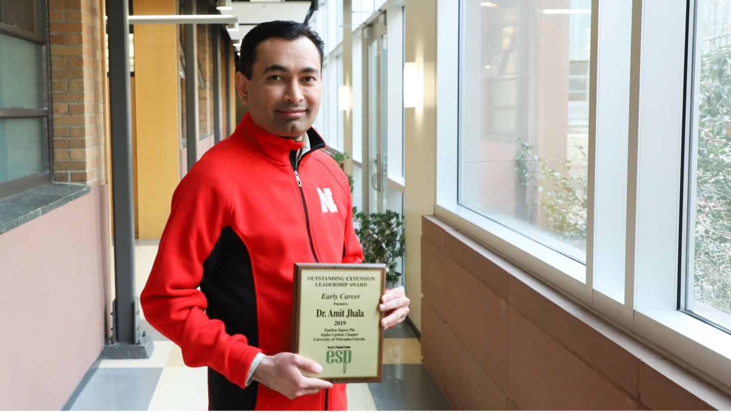 Amit Jhala holds his Epsilon Sigma Phi Early Career Outstanding Extension Leadership award plaque. 