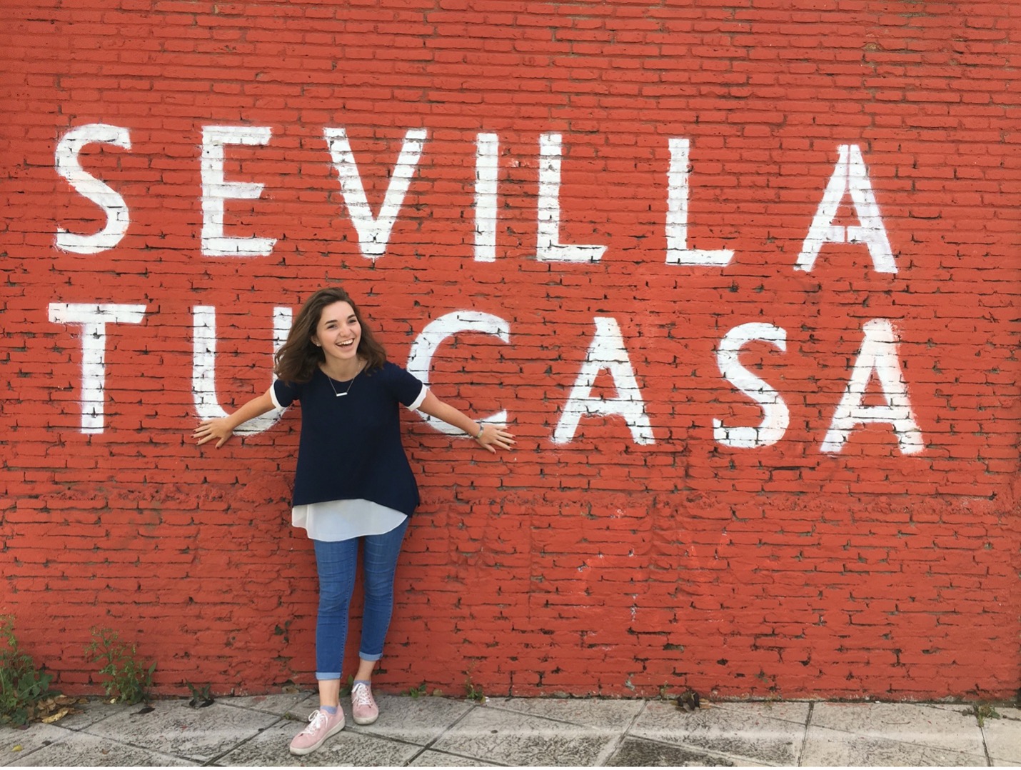 Joy Karges stands in front of wall in Sevilla, Spain.
