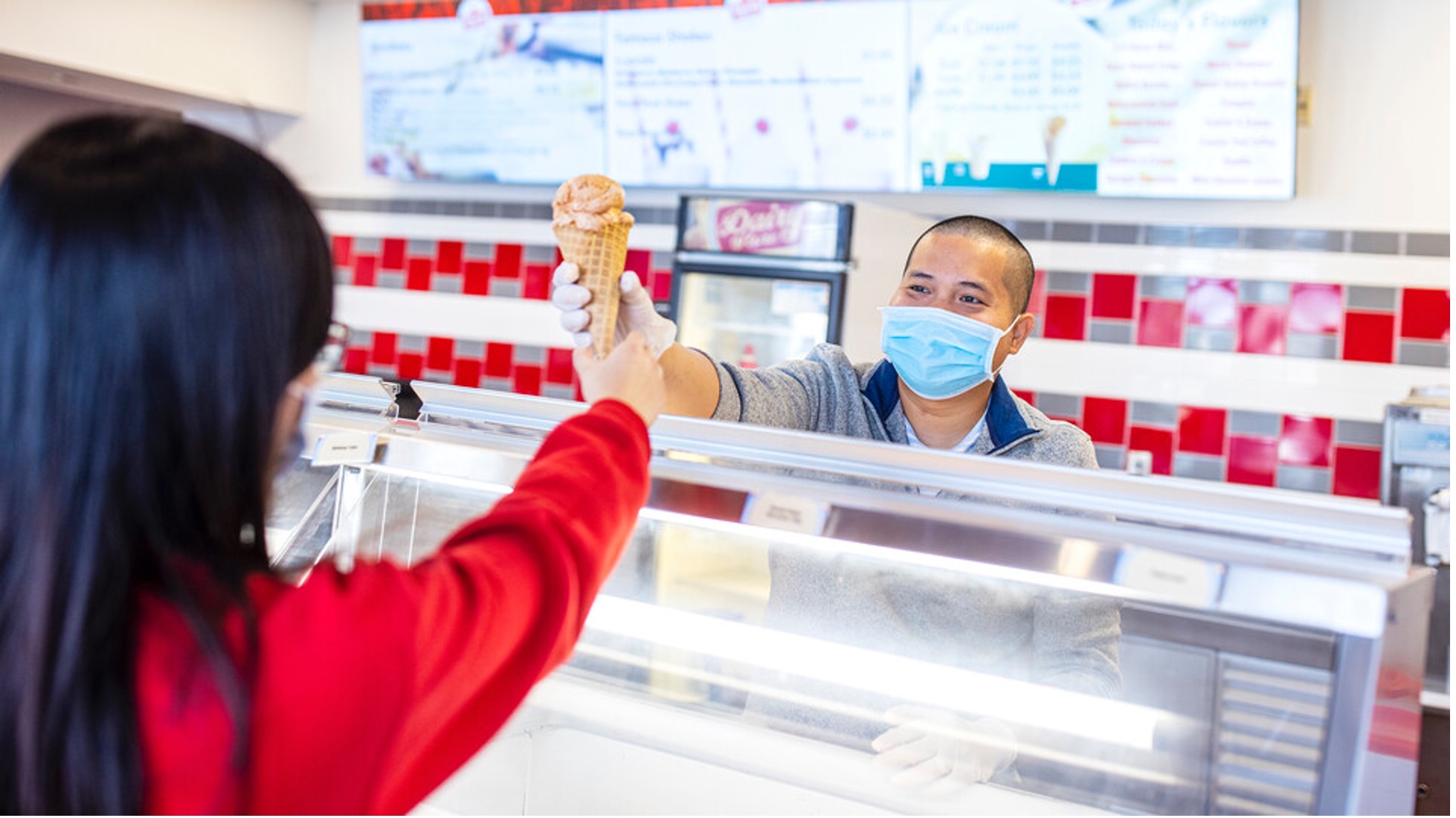 Duy Nguyen (right), manager of East Campus' Dairy Store, hands a cone of ice cream to a customer.