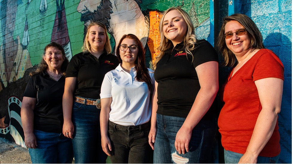 The three Rural Fellows and local partners pose in front of one of the downtown Chadron murals. Jenny Nixon (left), Chantelle Schulz, Hanna Jemison, Jacy Hafer and Kerri Rempp, tourism director for the Discover Northwest Nebraska.