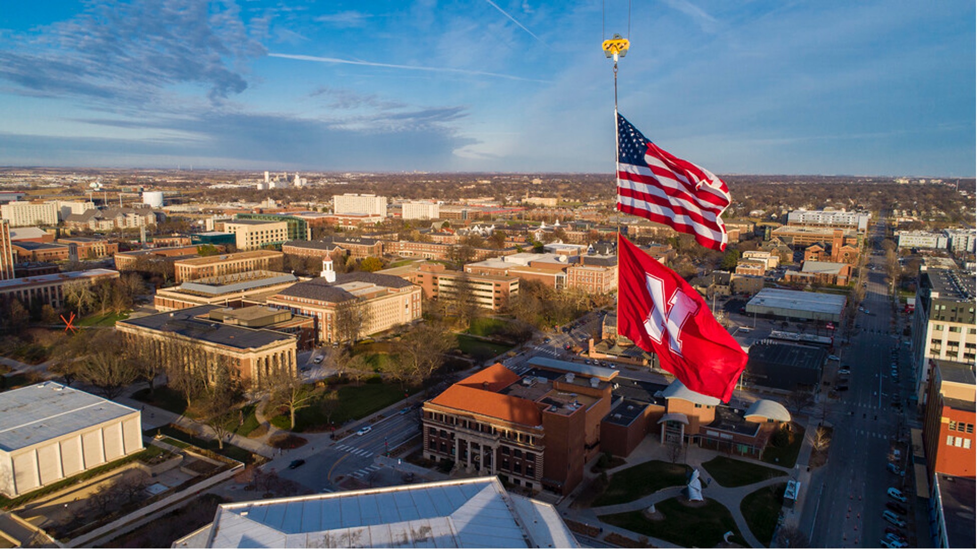 The United States and Husker flags fly from a Hausmann Construction crane in downtown Lincoln on a sunny Friday afternoon.