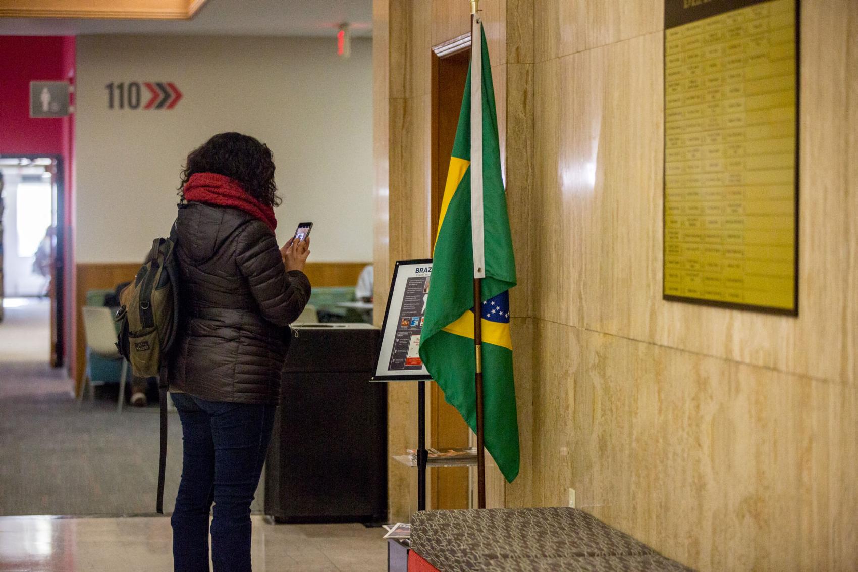 A student takes a photo of the Brazil flag in Love Library South during the International Education Week Annual Flag Hunt.