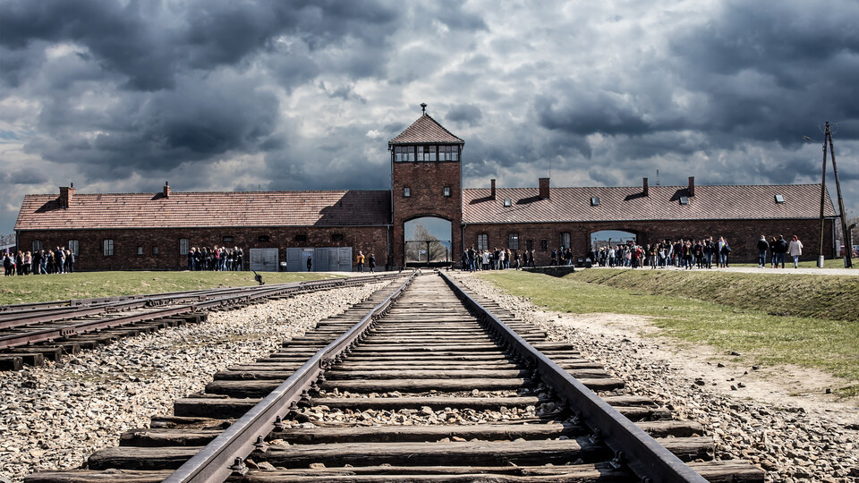 Visitors gather near the gate rail entrance, of Auschwitz Birkenau