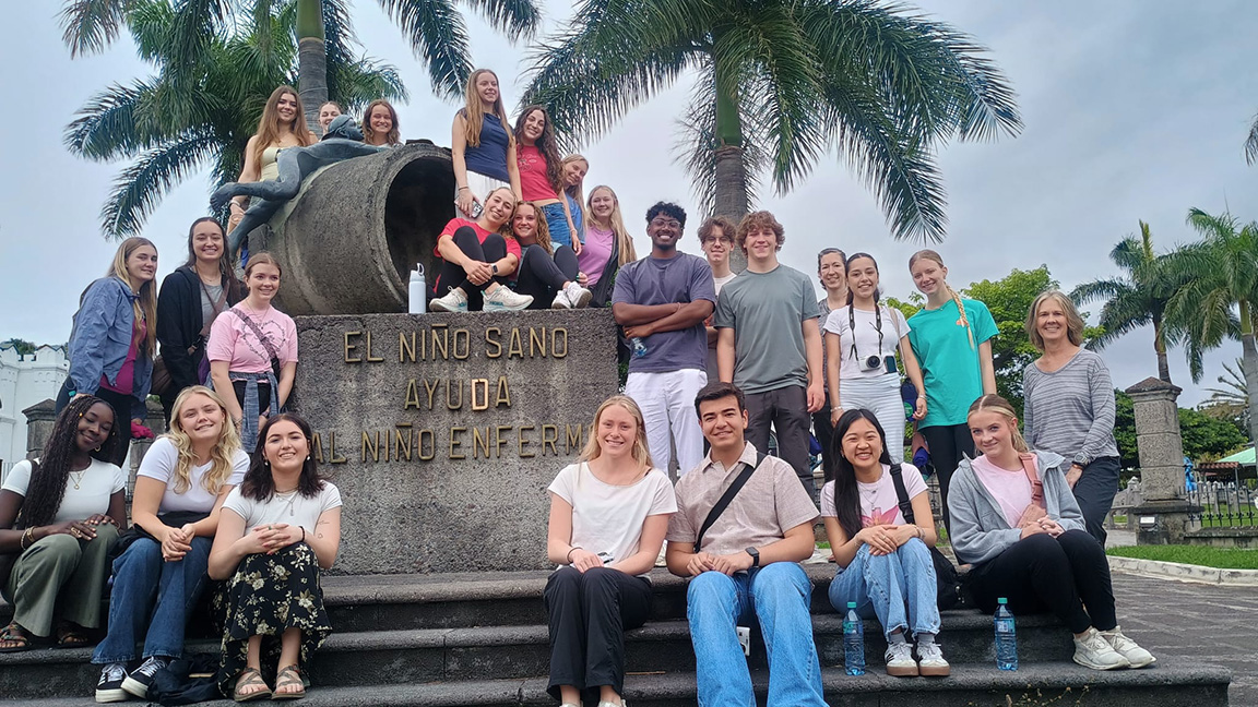 A group of students gather for a photo near a monument in Costa Rica