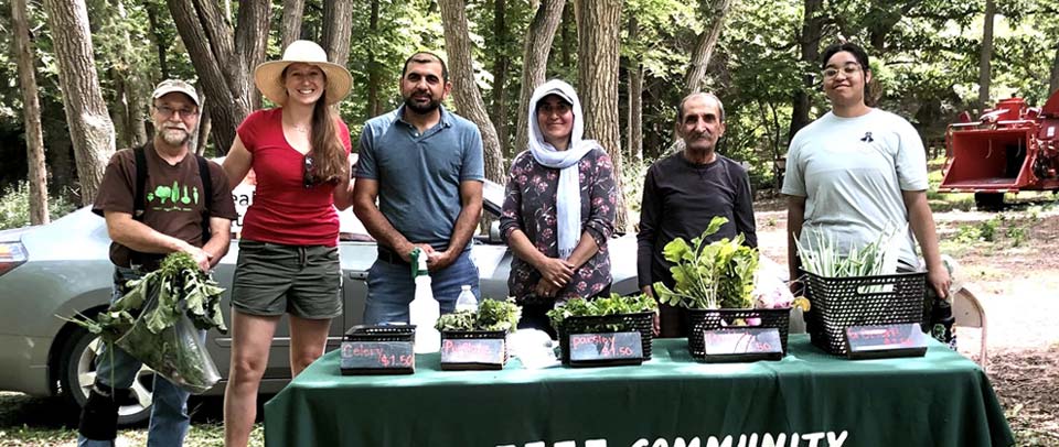 Yazidi global experiential learning group outdoors in front of table with plants