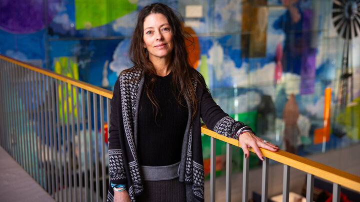 Rochelle Dalla, professor of child, youth and family studies at the University of Nebraska–Lincoln, poses next to a railing, with a colorful mural in the background.