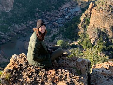 Katie Campbell sitting on rock in mountain area