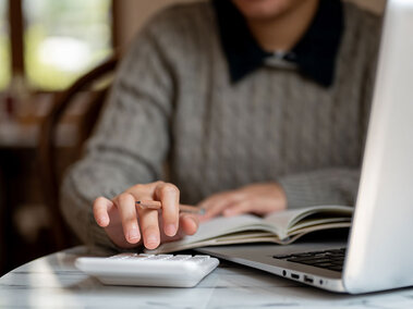 student at table with laptop and calculator