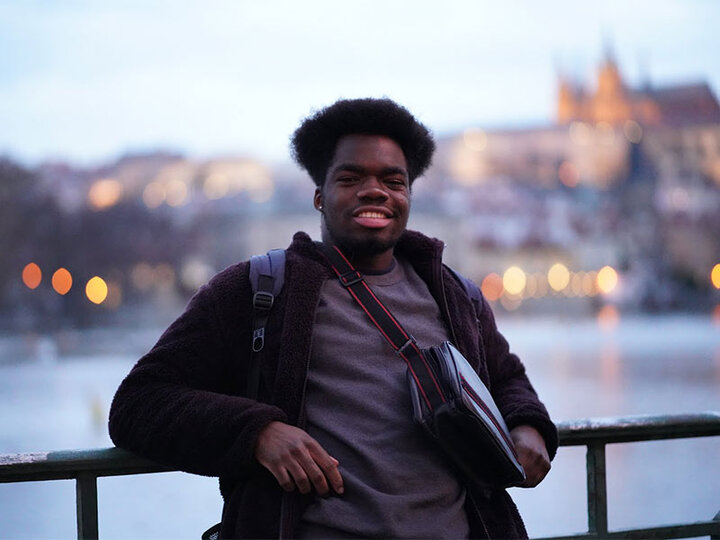 student leaning on rail by water in Prague, Czech Republic