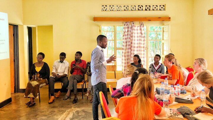 Student around a table listening to presentation.